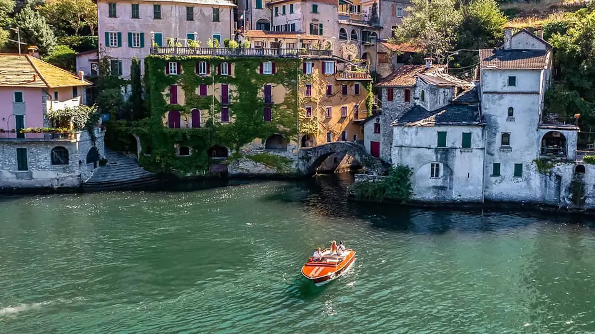 wooden boat gliding across lake Como Italy with views of Nesso town around on boat tour across the lake