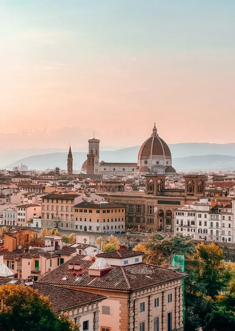 A panoramic view of Florence with terracotta rooftops stretching toward the Duomo under soft golden light