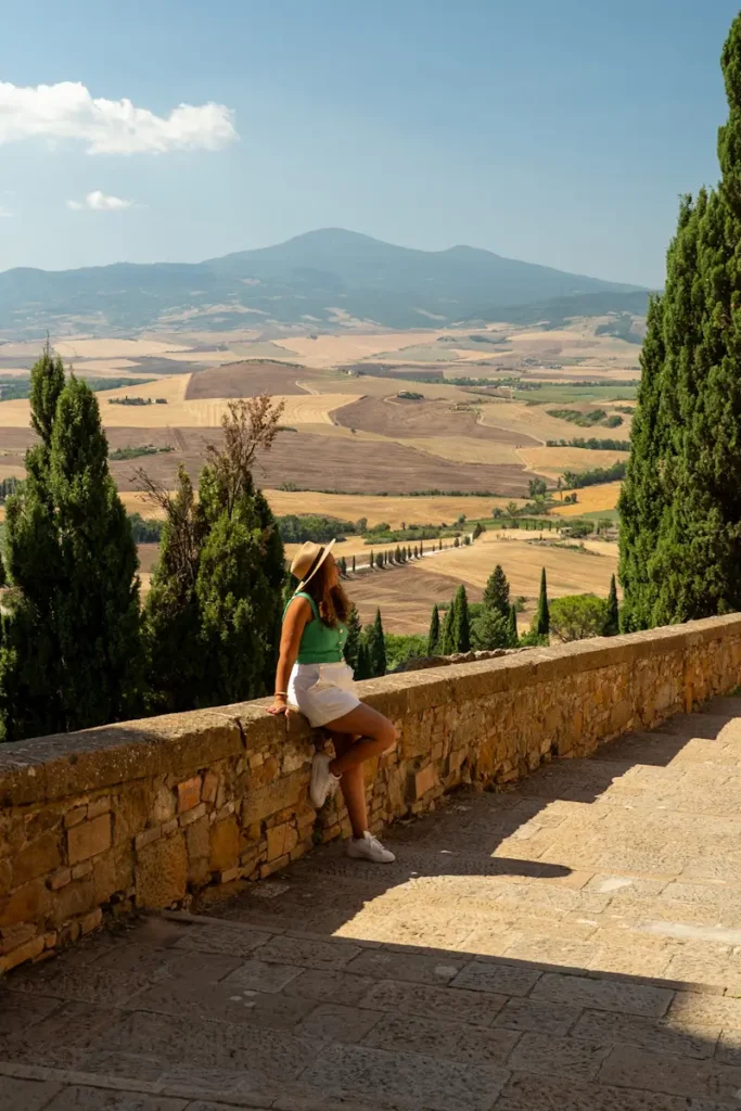 Florence 3 Days Itinerary: A Perfect Guide For First Timers Woman sitting on stone steps in Pienza Tuscany Italy wearing casual outfit and the views of the rolling here around is breathtaking