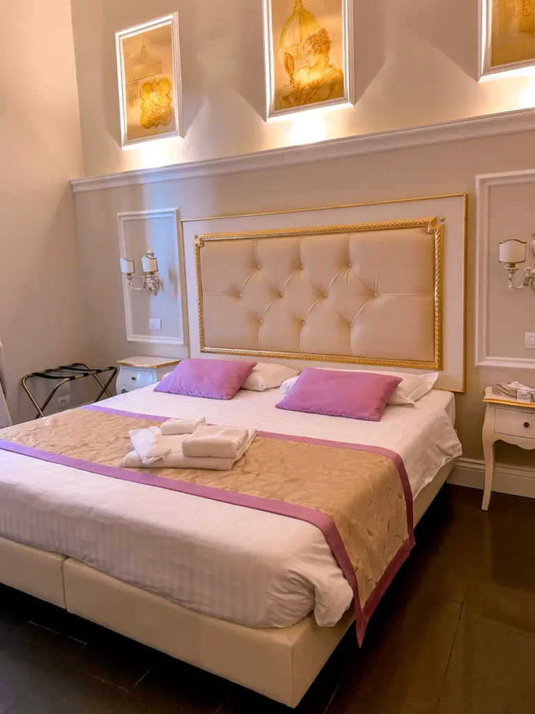 Cozy hotel bedroom with a tufted headboard, warm lighting, and neatly made bed, likely part of the stay featured in a B and b la terraza sul duomo review. Soft neutral tones and framed wall art create a comfortable, inviting atmosphere.