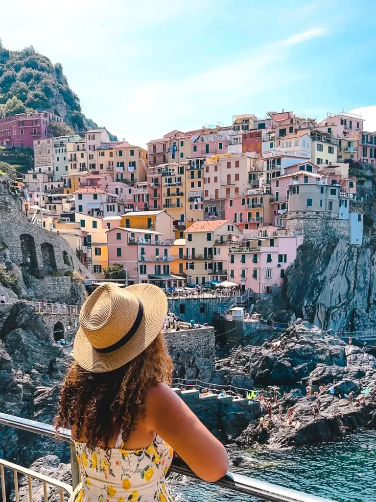 Best Cinque Terre Tour From Florence: Review & My Experience woman standing looking at the Scenic viewpoint overlooking colourful houses, dramatic cliffs, and sparkling blue sea in Vernazza, Cinque Terre Italy